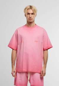 Tricou din bumbac roz cu efect de gradient, mâneci scurte și guler rotund. Are imprimeuri în culoare contrastantă pe față.