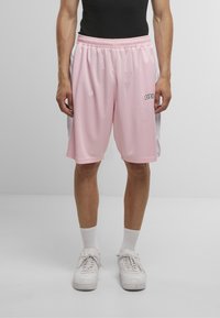 Shorts de sport roses avec une texture en maille, taille �élastique et panneaux latéraux blancs. Présente un petit logo "DEEP" sur le devant.