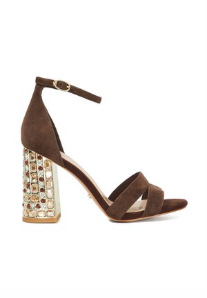 Brown suede high-heel sandal with three cross-straps and an ankle strap. Features a crystal-embellished block heel for added detail.