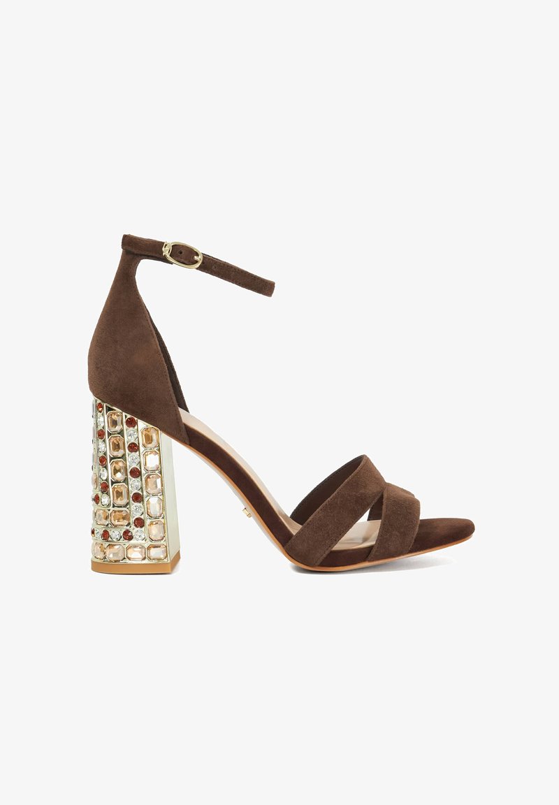 Brown suede high-heel sandal with three cross-straps and an ankle strap. Features a crystal-embellished block heel for added detail.