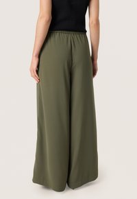 Green wide-leg trousers with a smooth texture, elastic waistband, and a relaxed fit, featuring a full-length design and subtle drape.