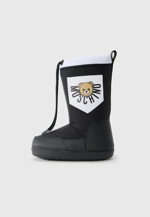 Botte isolée noire avec une tige rembourrée, présentant une patch blanche avec un graphique d'ours et le texte "Moschino", ainsi qu'une semelle en caoutchouc texturée.