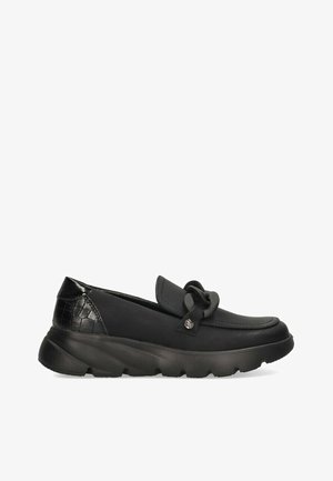 Zapatos negros de tipo slip-on con parte superior de cuero liso y un tacón texturizado con patrón de cocodrilo brillante. Cuentan con una suela de goma y un detalle decorativo de nudo.
