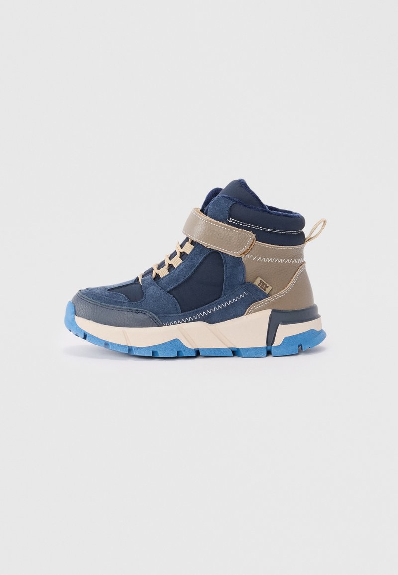 Mid-Top-Sportschuhe aus einer Kombination von marineblauem Wildleder und braunem Leder. Die Sohle ist blau, mit kontrastierenden Texturen und einem Klettverschluss.