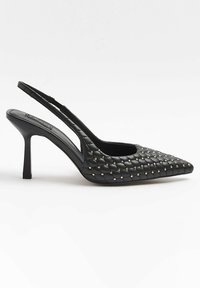 Escarpin slingback en cuir noir matelassé à talon haut, bout pointu et petits clous dorés sur le dessus, présenté en vue latérale sur fond blanc.