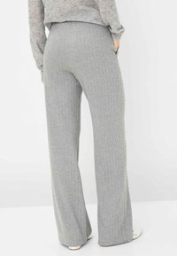 Grijze visgraat broek met een ontspannen pasvorm en zakken. De stof heeft een zachte textuur en een subtiel patroon, met een licht uitlopende pijp.