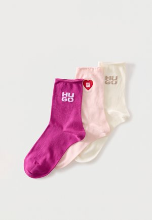 Trois paires de chaussettes mi-mollet en magenta, rose pâle avec un cœur rouge et crème, chacune avec le mot "HUGO" brodé près du bord-côte.