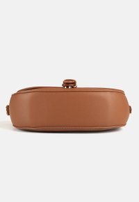 Sac à main en cuir marron posé à plat, montrant une base lisse texturée avec des bords cousus et une petite fermeture métallique sur le dessus.