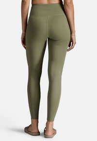 Olivgrüne Leggings, hoch tailliertes Design, glatte Textur, dehnbares Material, knöchellang, ohne sichtbare Muster oder Beschläge.