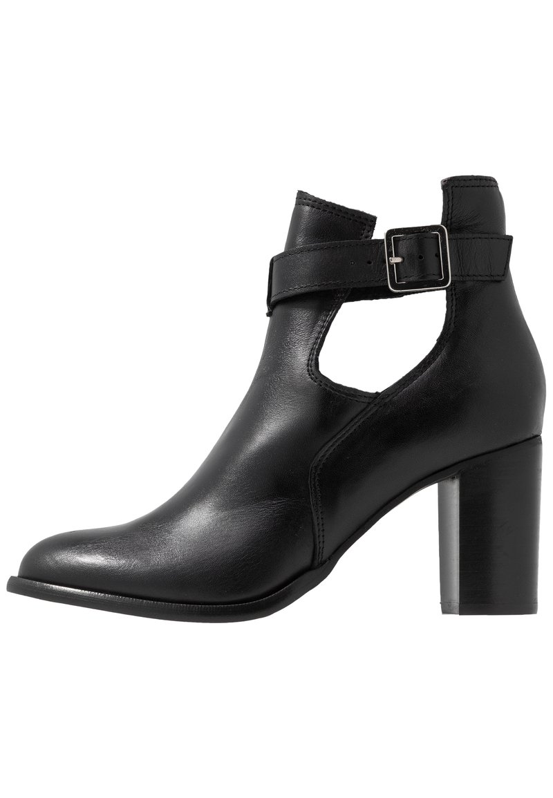 Bottine en cuir noir avec côtés découpés, bride à boucle argentée et talon moyen large.
