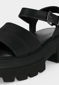 Μαύρο chunky platform σανδάλι με παχιά λουριά, κούμπωμα με πόρπη και ανθεκτική σόλα για επιπλέον πρόσφυση και στυλ.