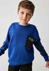 Niebieska bluza z teksturowaną czarną kieszenią z logo "BAKER", długimi czarnymi rękawami i okrągłym dekoltem. Casualowy design dla chłopców.