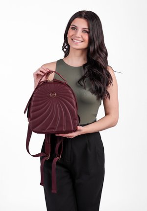 Bordeauxfarbene Kunstleder-Rucksack mit einem gesteppten Spiraldesign, Oberhandgriff und verstellbaren Trägern. Mit goldfarbenem Logo-Akzent auf der Vorderseite.