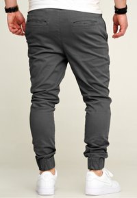 Gray sweatpants with elastic cuffs and pockets, made from a soft material, paired with white sneakers for a casual look.