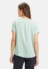 Mintgrünes kurzärmeliges Blusenoberteil aus weichem Material, mit einem geometrischen Muster und einem abgerundeten Saum. Die Rückansicht zeigt eine lässige Passform.