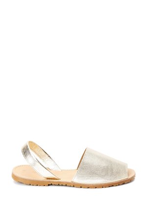 Sandales à enfiler en métal doré avec un orteil ouvert, dessus en cuir souple et deux bretelles ajustables à l'arrière. Semelle en caoutchouc naturel avec finition texturée.