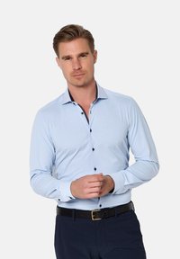 Lichtblauw longsleeve shirt met een slim fit. Heeft een zwarte knoopsluiting en een contrasterende donkere kraag. Soepele stofstructuur.