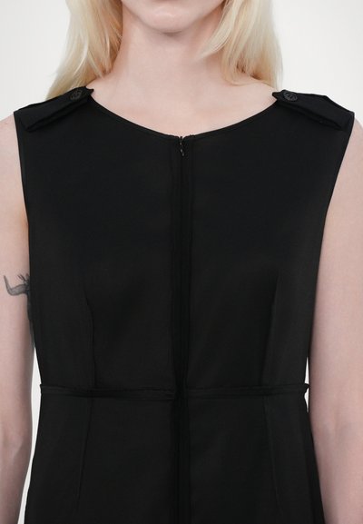Robe noire sans manches avec un col montant, fermeture éclair à l'avant et boutons décoratifs sur les épaules. Tissu lisse avec une silhouette ajustée.