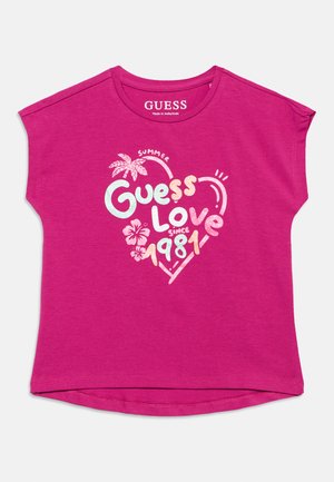 T-shirt à manches courtes rose vif avec le texte "Guess Love depuis 1981", graphiques estivaux d'un palmier et d'une fleur d'hibiscus sur le devant.