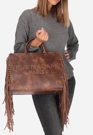 Borsa a tracolla in pelle marrone con dettagli frangiati, testo impresso "RUE MADAM PARIS", forma strutturata e due manici robusti.
