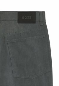 Grau denim Hose mit einem schwarzen Leder-Waistband-Label, das mit "BOSS" gekennzeichnet ist, und einer einzelnen Gesäßtasche mit sichtbaren Nähten.
