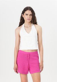 White halter top paired with bright pink textured crochet shorts featuring an elastic waistband and drawstring detail.