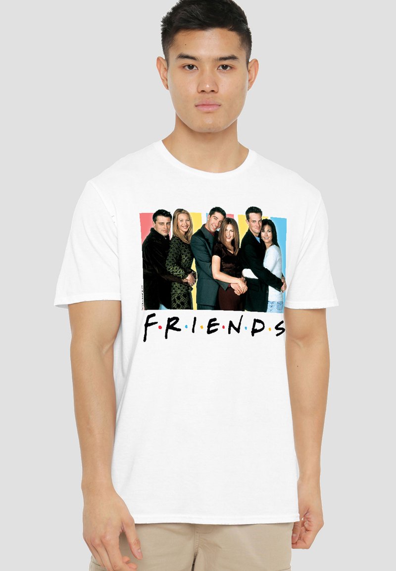 Man wearing white t-shirt with cast photo of six adults standing close, colorful background, and "FRIENDS" text below.