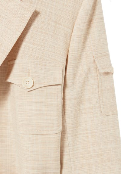 Blazer beige en tissu texturé, doté de deux poches avant et d'une fermeture à un bouton. Remarquable par son design ajusté et ses revers classiques.