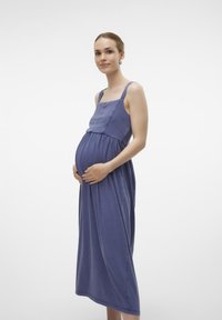 Sukienka ciążowa z miękkiego fioletowego materiału, z regulowanymi ramiączkami, dopasowanym topem i zwiewną spódnicą, dostosowująca się do kształtu ciała w ciąży.