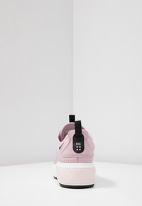 Rosa Nike-sneakers med en texturerad ovandel, kontrasterande svarta detaljer, en dragöppning och en slät vit och svart sula.