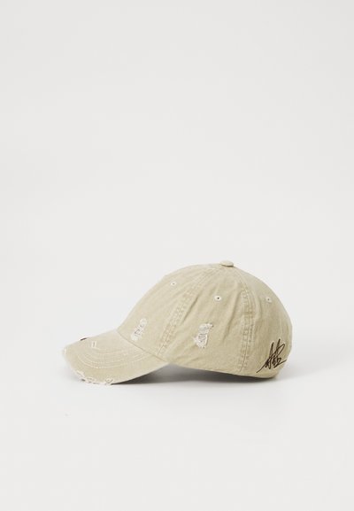 Beige Baumwoll-Baseballmütze mit gestickten Details, darunter kleine Designs auf der Vorderseite und eine Unterschrift an der Seite. Mit abgenutzten Akzenten.