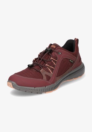 Scarpa sportiva rossa in rete con punta arrotondata, suola in gomma grigia, sistema di bloccaggio dei lacci e sottili accenti beige sui lati e sulla linguetta.