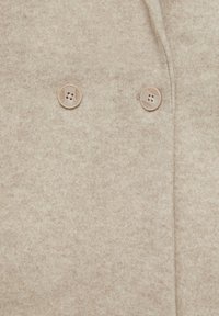 Tissu beige en mélange de laine avec une surface légèrement texturée, équipé de deux boutons de couleur claire pour la fermeture près du haut.