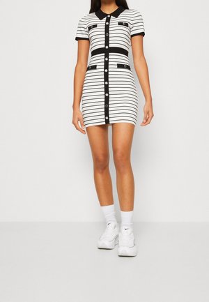 Dopasowana sukienka z krótkim rękawem w czarno-białe poziome paski, z guzikami z przodu, dwoma kieszeniami na piersi i prążkowanym kołnierzem.