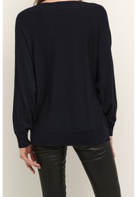 Dark navy oversized sweater in soft knit material, featuring a ribbed hem and cuffs, with a relaxed silhouette and long sleeves.