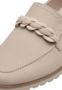 Beige skinnloafers med flettet stroppdetalj, synlig søm og teksturert såle for grep. Flat design og avrundet tå.