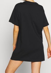 Czarna oversize sukienka T-shirt z bawełny, z okrągłym dekoltem i krótkimi rękawami, z prostym dołem, który sięga w połowie uda.