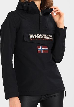 Czarna bluza z suwakiem z przodu, naszywką z logo Napapijri, naszywką z norweską flagą, noszona przez osobę dotykającą kołnierza.