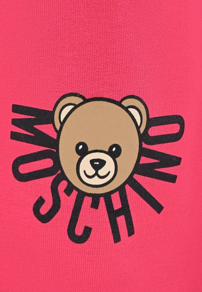 Felle roze stof met een cartoonbeer in bruin en zwart, met daaromheen gedurfde "MOSCHINO" tekst rond het gezicht van de beer. Gladde textuur.