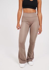 Leggings a vita alta in moka realizzati in tessuto elasticizzato con una finitura liscia. Design svasato dal ginocchio, con un delicato dettaglio di cucitura.