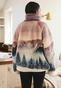 Fleece jacket featuring pastel mountain and forest print in shades of pink, blue, and cream. High collar and soft texture.