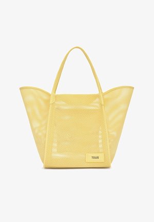 Borsa tote gialla in rete con apertura ampia e due manici, con una piccola etichetta rettangolare con la scritta "TOUS" nella parte inferiore frontale.