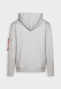 Sudadera gris claro con capucha ajustable, puños y dobladillo acanalados. Presenta un distintivo decorativo en la manga izquierda y detalles de logo texturizados en la parte trasera.