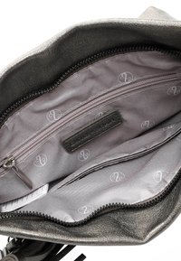 Metallic gray handbag interior features a smooth, textured fabric with a zippered pocket and printed logo pattern. Accented with black zipper.