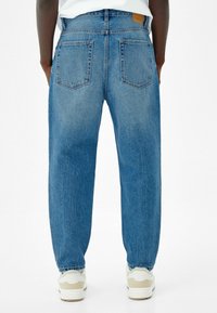 Ljusblå denimjeans med avslappnad passform, synlig sömnad, två bakfickor och en tanlätt läderetikett på midjan.