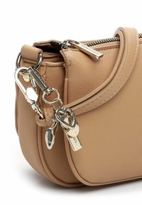 Beige Lederhandtasche mit strukturierter Oberfläche, ausgestattet mit einem oberen Reißverschluss, silbernen Beschlägen und dekorativen Schlüsselanhängern in Herz- und Schlossform.