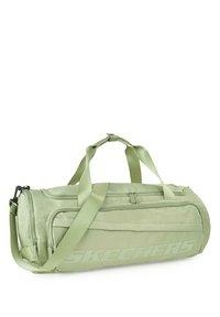 Bolsa de lona verde con dos asas, correa de hombro ajustable y un bolsillo con cremallera en la parte frontal. Presenta el logotipo de la marca en relieve en un lado.