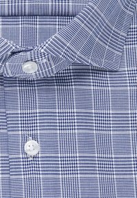 Niebiesko-biała koszula w kratę z kołnierzykiem zapinanym na guziki, z motywem siatki i gładką teksturą. Widoczne białe guziki.