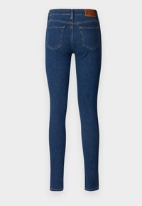 Tynne jeans i mørkeblå denim. Har en brun lærlapp bak, to baklommer og en jevn tekstur med subtile sømdetaljer.