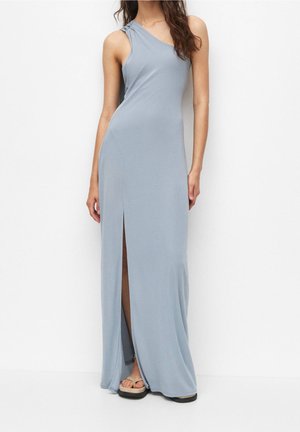 Kobieta w jasnoniebieskiej, bezrękawnikowej sukni maxi z rozcięciem do uda, stoi na białym tle.